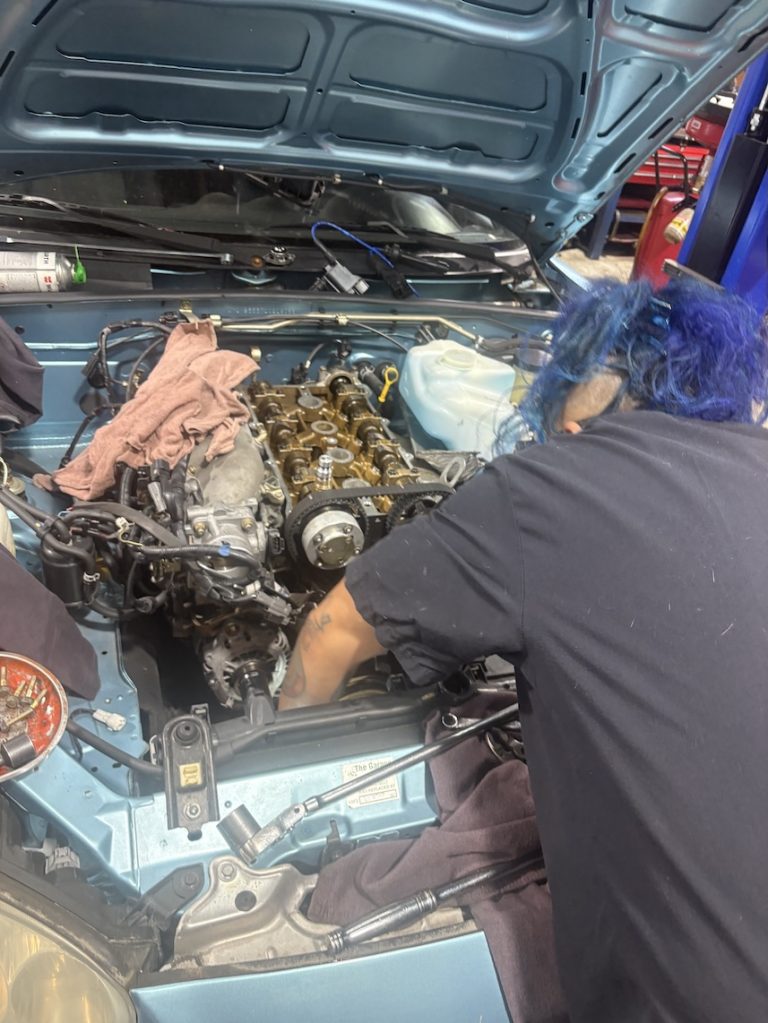 Auto technician replacing the timing belt on a Mazda Miata